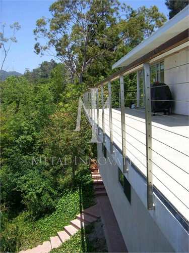 <p>This is a side mounted stainless steel cable rail with a teak wood top rail. Side mounting the rail achieves that infinity edge look and makes the deck look larger. The mounting plates are recessed into the stucco preventing water and moister penetration.</p>
